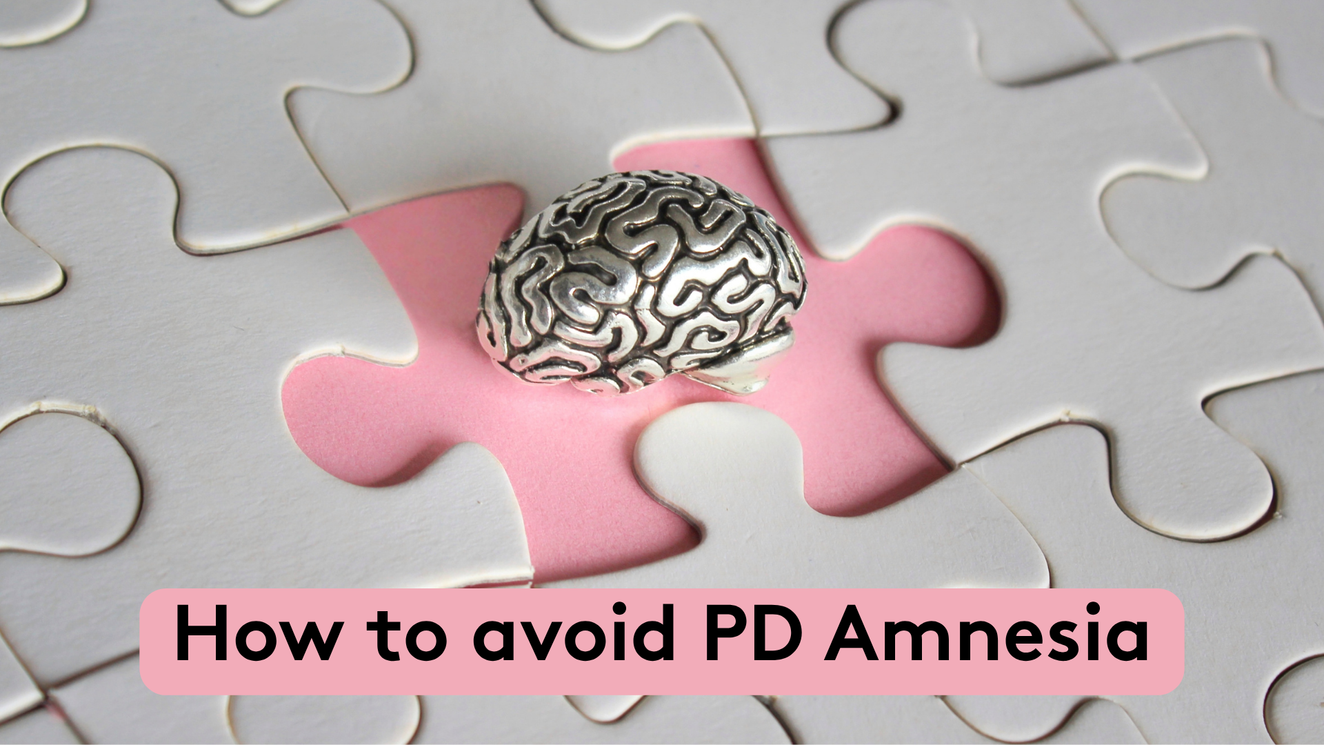 Close-up of a silver brain-shaped object placed on a pink puzzle piece surrounded by white puzzle pieces, with the text “How to avoid PD Amnesia” at the bottom.